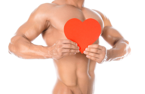 Bodybuilding and Health: handsome strong bodybuilder holding a paper card red heart isolated on a white background in studio - Photo, image