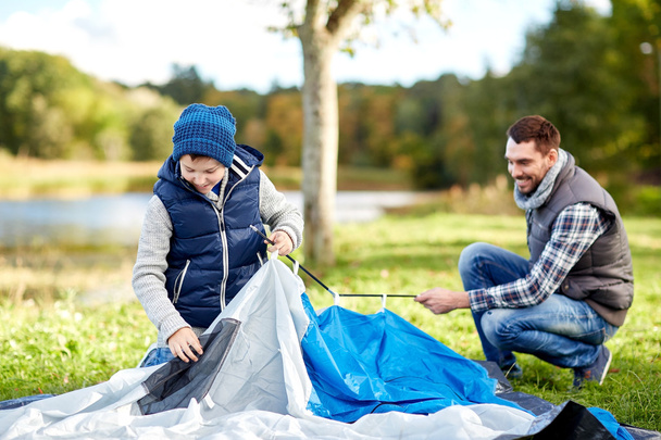 happy father and son setting up tent outdoors - Photo, Image