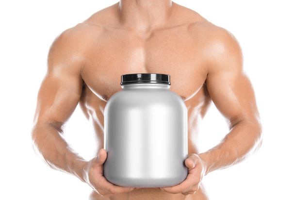Bodybuilding and Sports theme: handsome strong bodybuilder holding a plastic jar with a dry protein and showing gesture isolated on white background in studio - Foto, immagini