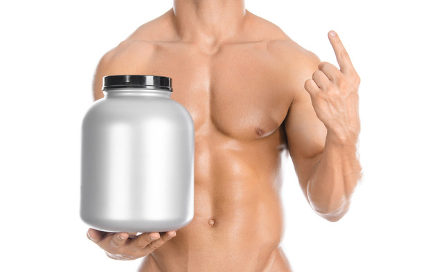 Bodybuilding and Sports theme: handsome strong bodybuilder holding a plastic jar with a dry protein and showing gesture isolated on white background in studio - Фото, зображення