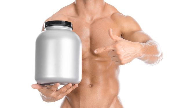 Bodybuilding and Sports theme: handsome strong bodybuilder holding a plastic jar with a dry protein and showing gesture isolated on white background in studio - Φωτογραφία, εικόνα
