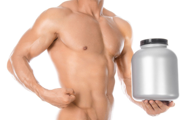 Bodybuilding and Sports theme: handsome strong bodybuilder holding a plastic jar with a dry protein and showing gesture isolated on white background in studio - Foto, Imagem
