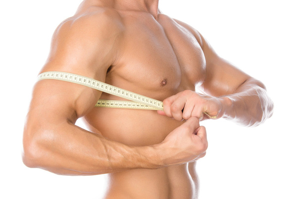Bodybuilding and Sports theme: handsome strong bodybuilder holding centimeter tape to measure body isolated on white background in studio - Φωτογραφία, εικόνα