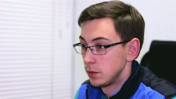 Mladý muž v brýlích funguje za počítač - Záběry, video