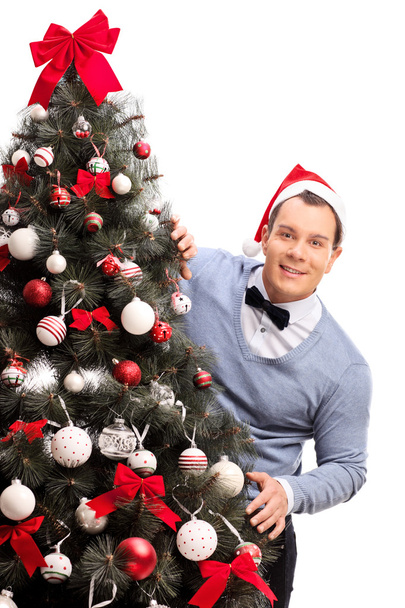 Man with Santa hat behind a Christmas tree - Foto, Imagem
