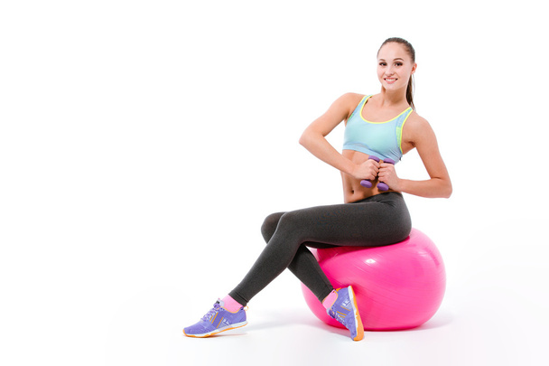 Joven deportista haciendo ejercicio con mancuernas sentadas en el fitball
 - Foto, imagen