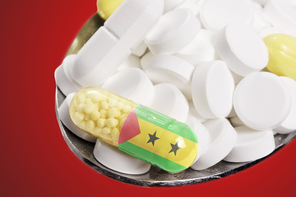 Ложка, полная таблеток и капсула с флагманом Сан-Тома
 - Фото, изображение