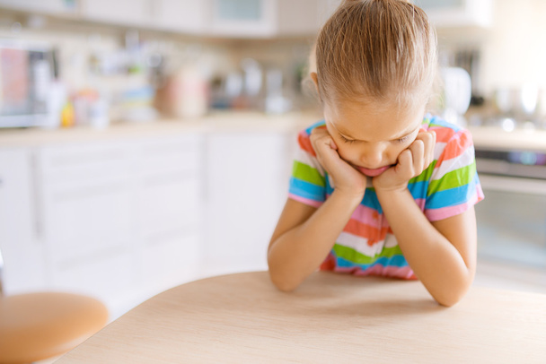 menina sentada à mesa e triste
 - Foto, Imagem