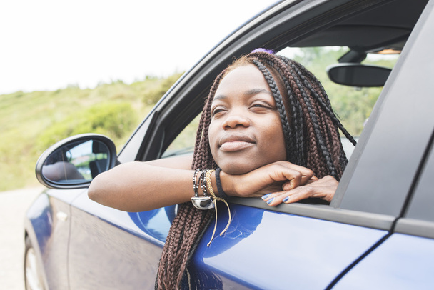 Portret van mooie Afrikaanse vrouw op zoek uit de auto ramen. - Foto, afbeelding