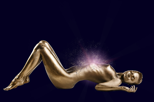 Γυμνή γυναίκα με χρυσό γυαλιστερό δέρμα που βρίσκεται - Φωτογραφία, εικόνα