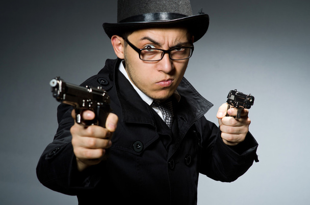 Criminal en abrigo negro sosteniendo hadgun contra gris
 - Foto, Imagen