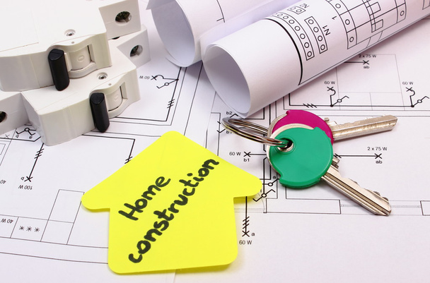 Haus aus gelbem Papier, Schlüssel, elektrischer Sicherung und Bauzeichnung - Foto, Bild