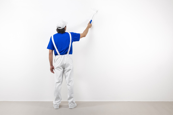 Painter with paintroller on white wall - Photo, Image