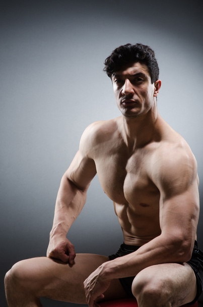 Muskulöser Mann posiert im dunklen Studio - Foto, Bild