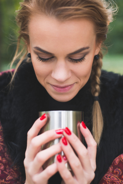 Giovane donna bere tè caldo o caffè all'aperto nel parco autunnale
 - Foto, immagini