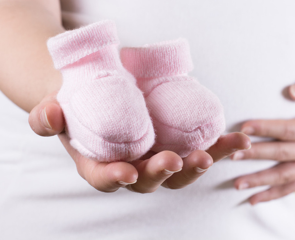 Femme enceinte tenant paire rose chaussures pour bébé fille
 - Photo, image
