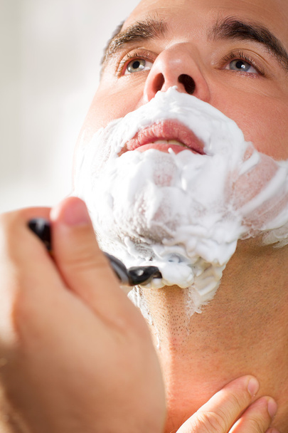 Handsome young man is shaving his face - Fotó, kép