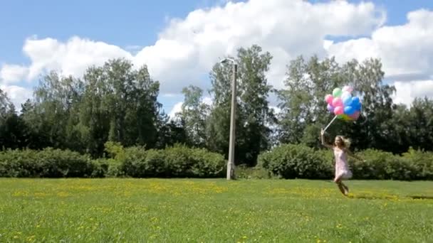 mladá krásná žena, běhu a skákání s barevnými balónky v parku - Záběry, video