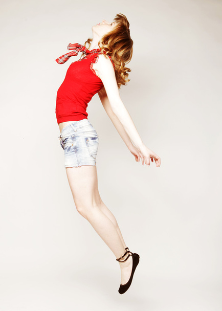 young lady jumping in joy over grey  background - Foto, Imagem