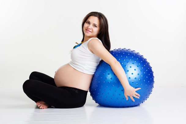 Menina grávida está segurando fitball perto de suas costas
 - Foto, Imagem