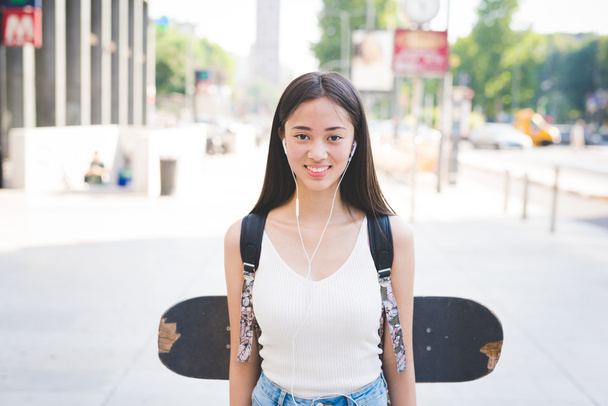 Beautiful asiatic skater woman in city - 写真・画像