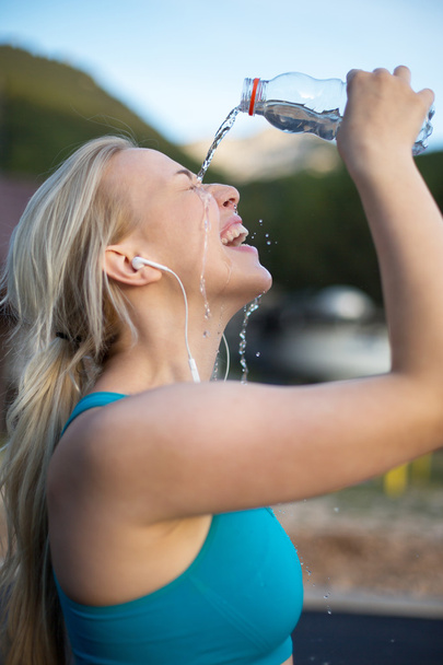 Fitnessläuferin trinkt und spritzt Wasser ins Gesicht. f - Foto, Bild
