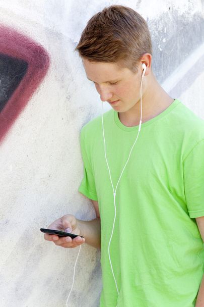Teen chłopiec z słuchawki w pobliżu graffiti ściany - Zdjęcie, obraz