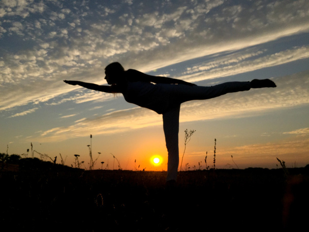 Femme équilibrage dans une jambe au coucher du soleil
. - Photo, image