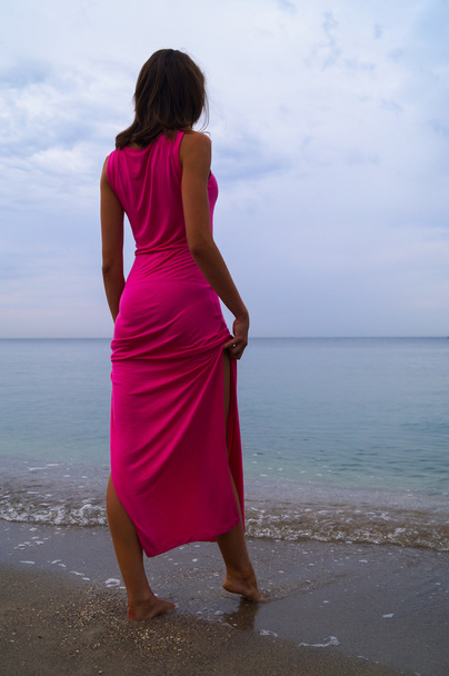 Menina bonita em vestido rosa de pé perto do mar
 - Foto, Imagem