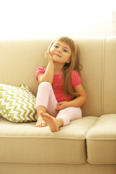 Beautiful little girl sitting on sofa - Fotoğraf, Görsel