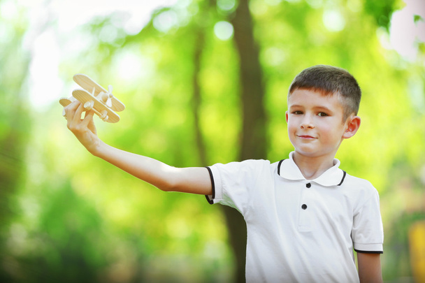 Little boy plays with wooden plane  - Foto, Bild