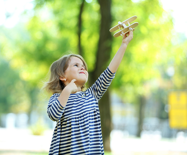 little girl plays with wooden plane - Fotografie, Obrázek