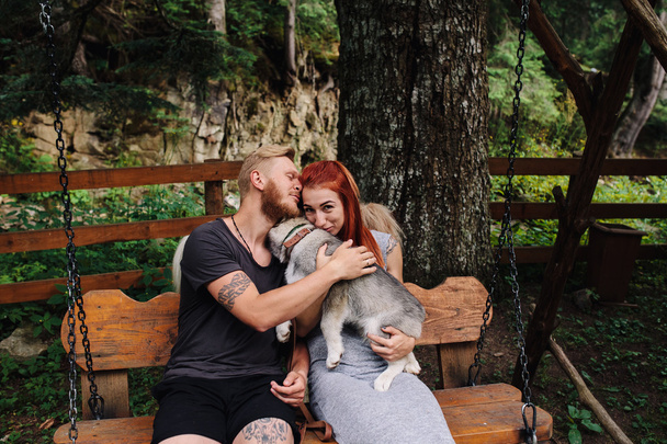 beautiful couple together with dog on a swing - Φωτογραφία, εικόνα