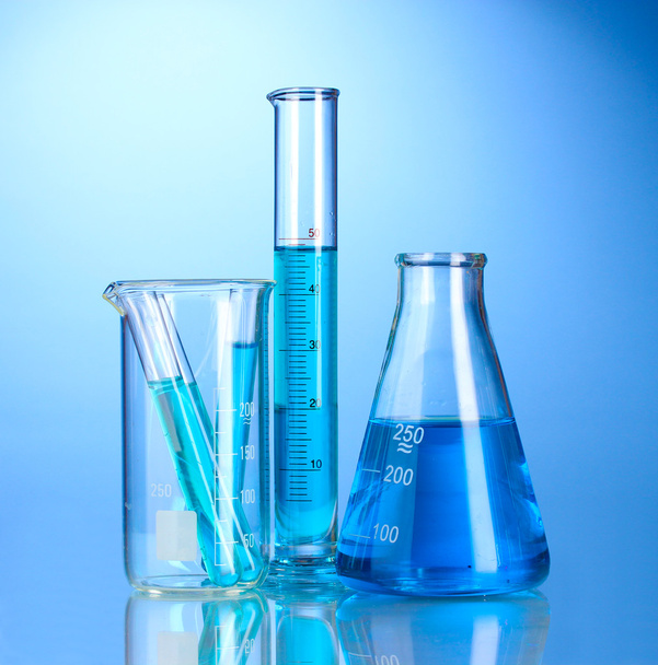 Laboratory glassware with blue liquid with reflection on blue background - Photo, image