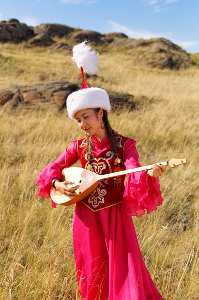 Piękna kobieta Kazachstanu w stroju ludowym w stepie, taniec z dombyra - Zdjęcie, obraz