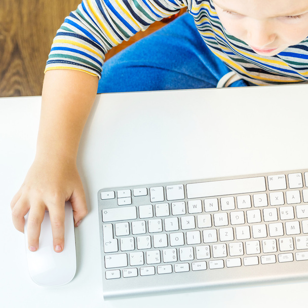 νεαρό αγόρι συνεργάζεται με το ποντίκι του υπολογιστή - Φωτογραφία, εικόνα