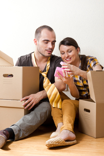 Молодая пара с коробками в новой квартире сидит на полу
 - Фото, изображение