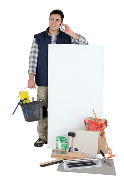 Tile cutter stood holding bucket next to blank panel - Foto, afbeelding