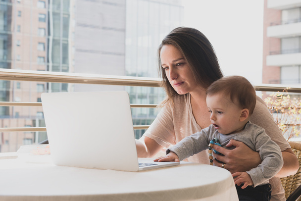 Mãe com seu filho enquanto trabalhava em seu laptop
 - Foto, Imagem