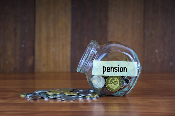 Coins and glass container with Pension label on wooden background. - Photo, Image