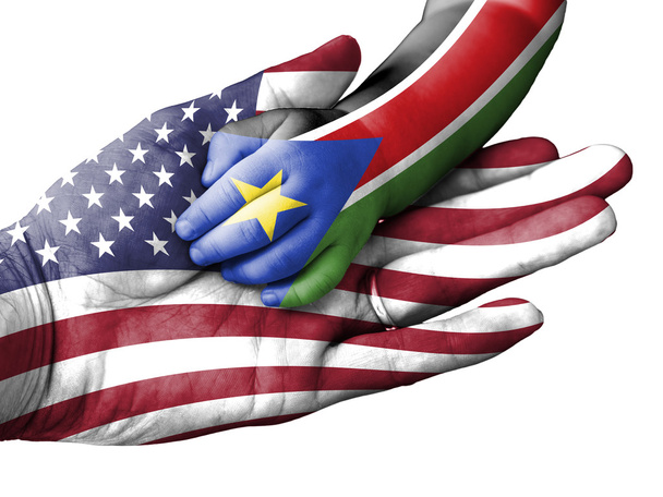 Adult man holding a baby hand with United States and South Sudan flags overlaid. Isolated on white - Photo, Image