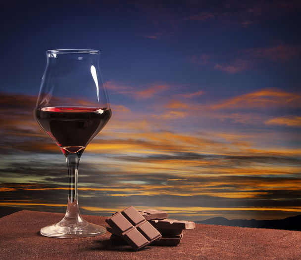 Wine glass and chocolate with colorful sunset - Φωτογραφία, εικόνα