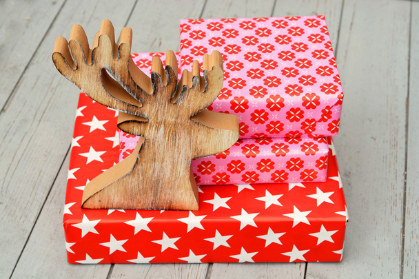Patrón de flores estrella roja y rosa regalos de Navidad con renos de madera sobre un fondo de estantes de madera
 - Foto, imagen