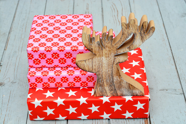 Patrón de flores estrella roja y rosa regalos de Navidad con renos de madera sobre un fondo de estantes de madera
 - Foto, imagen