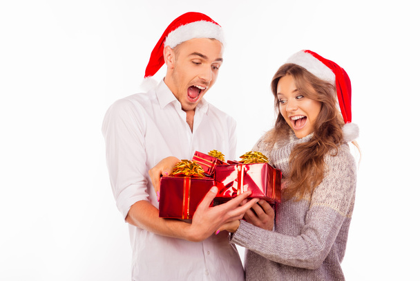 cheerful funny couples with santa hat holding red presents - Фото, зображення