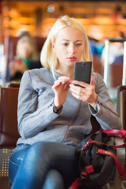Reisende benutzt Handy während der Wartezeit. - Foto, Bild