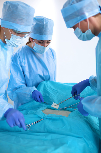 Команда хирурга в форме проводит операцию на пациенте в кардиохирургической клинике
 - Фото, изображение