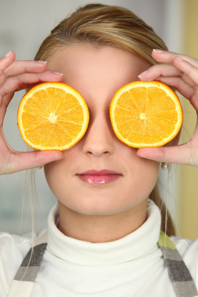 Young woman using orange halves as eyes - Foto, immagini