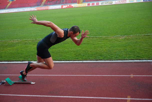 Athletic man start on track - Foto, afbeelding