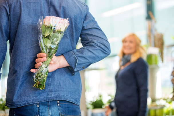 Man Hides Bouquet From Woman In Flower Shop - Фото, изображение